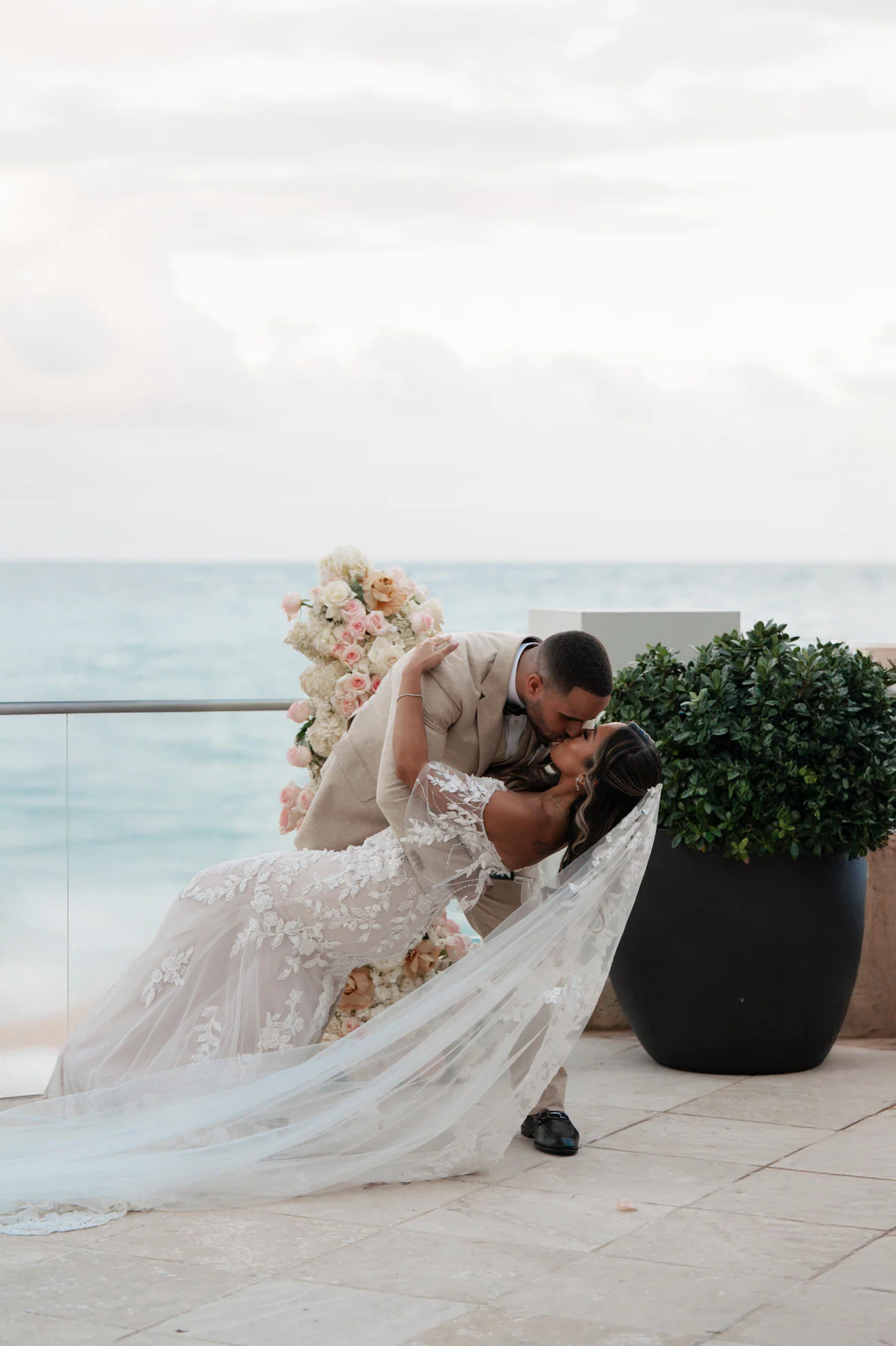A couple sharing a dip kiss beside the water in evening light
