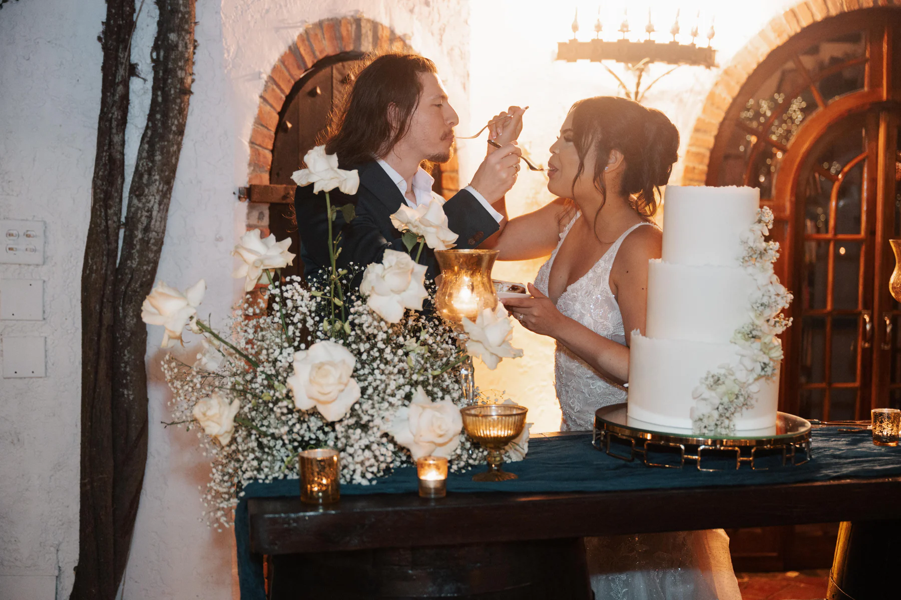 Abigail and Cody sharing a first bite of cake in the golden light at Hacienda Siesta Alegre