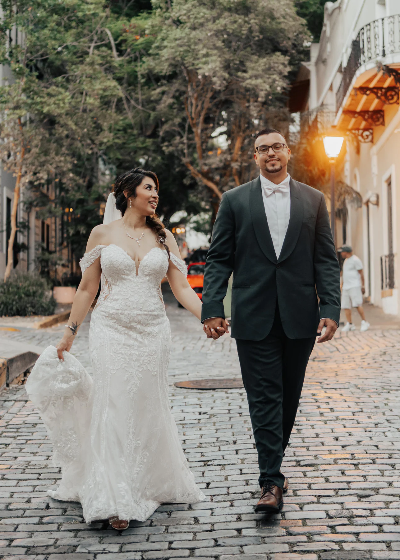 Alexandra and Freddie walking hand in hand down a cobblestone street in Old San Juan after their Hotel El Convento ceremony