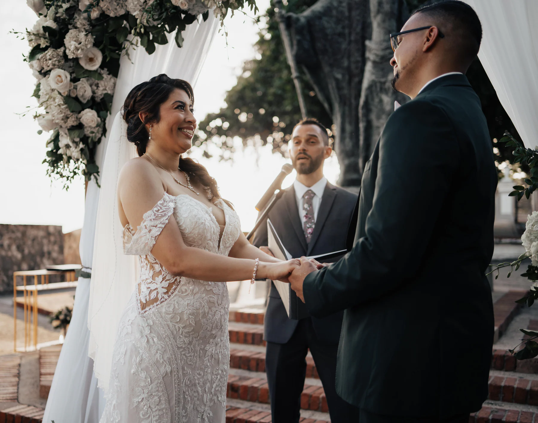 Alexandra and Freddie exchanging vows beneath a floral arch at their Hotel El Convento wedding ceremony